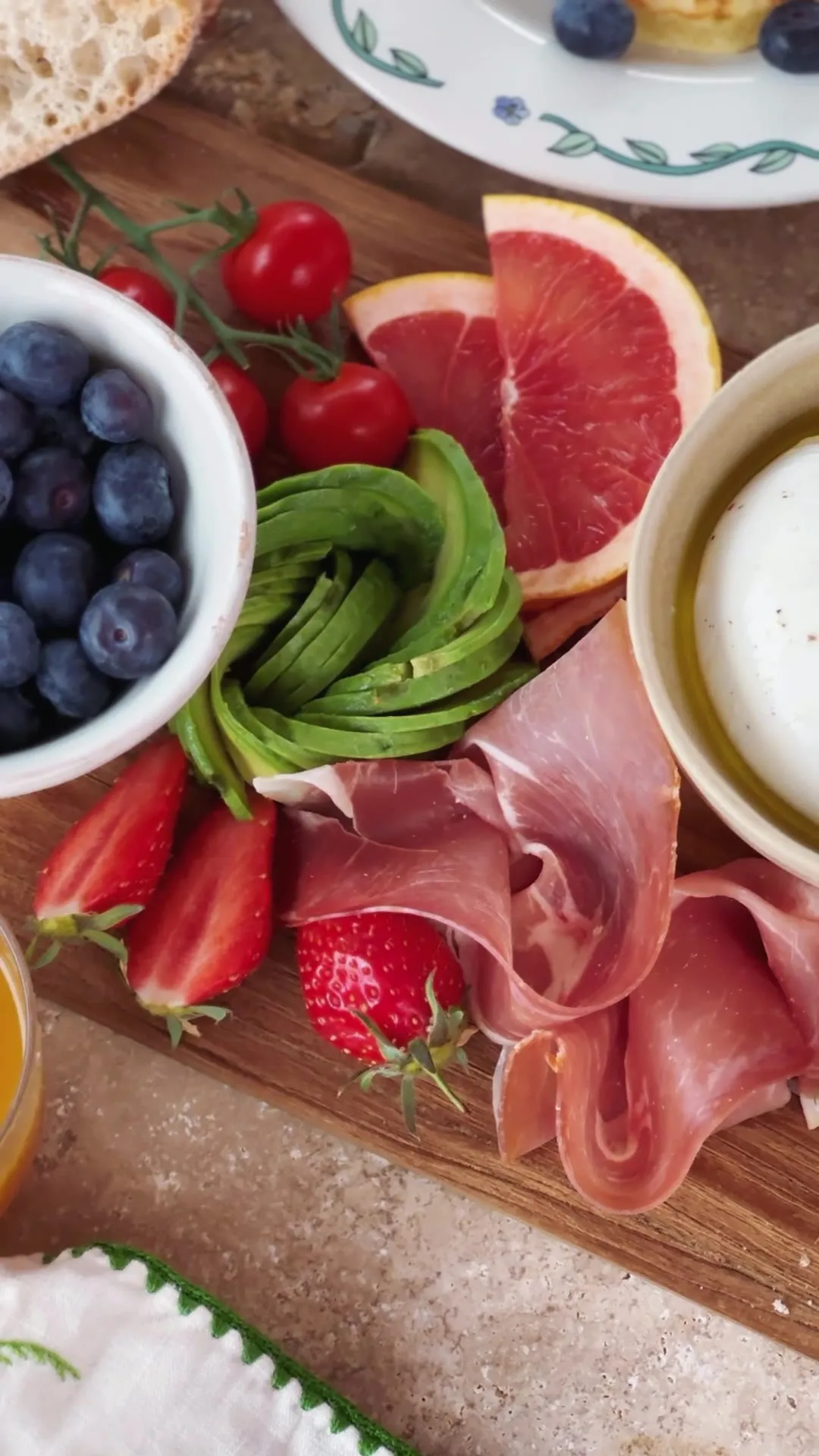 Table de brunch fleurie : fruits, avocat, jambon cru et café