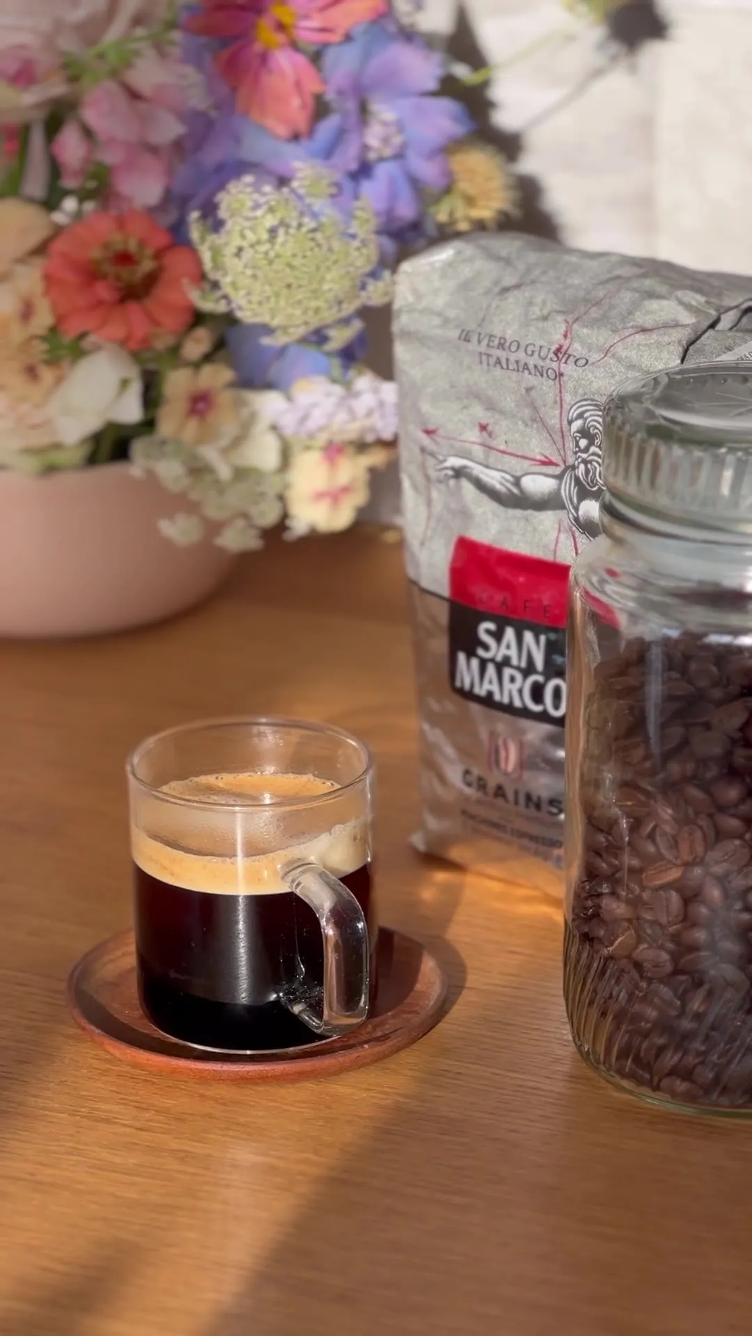 Grains de café moulus puis expresso servi dans une tasse en verre